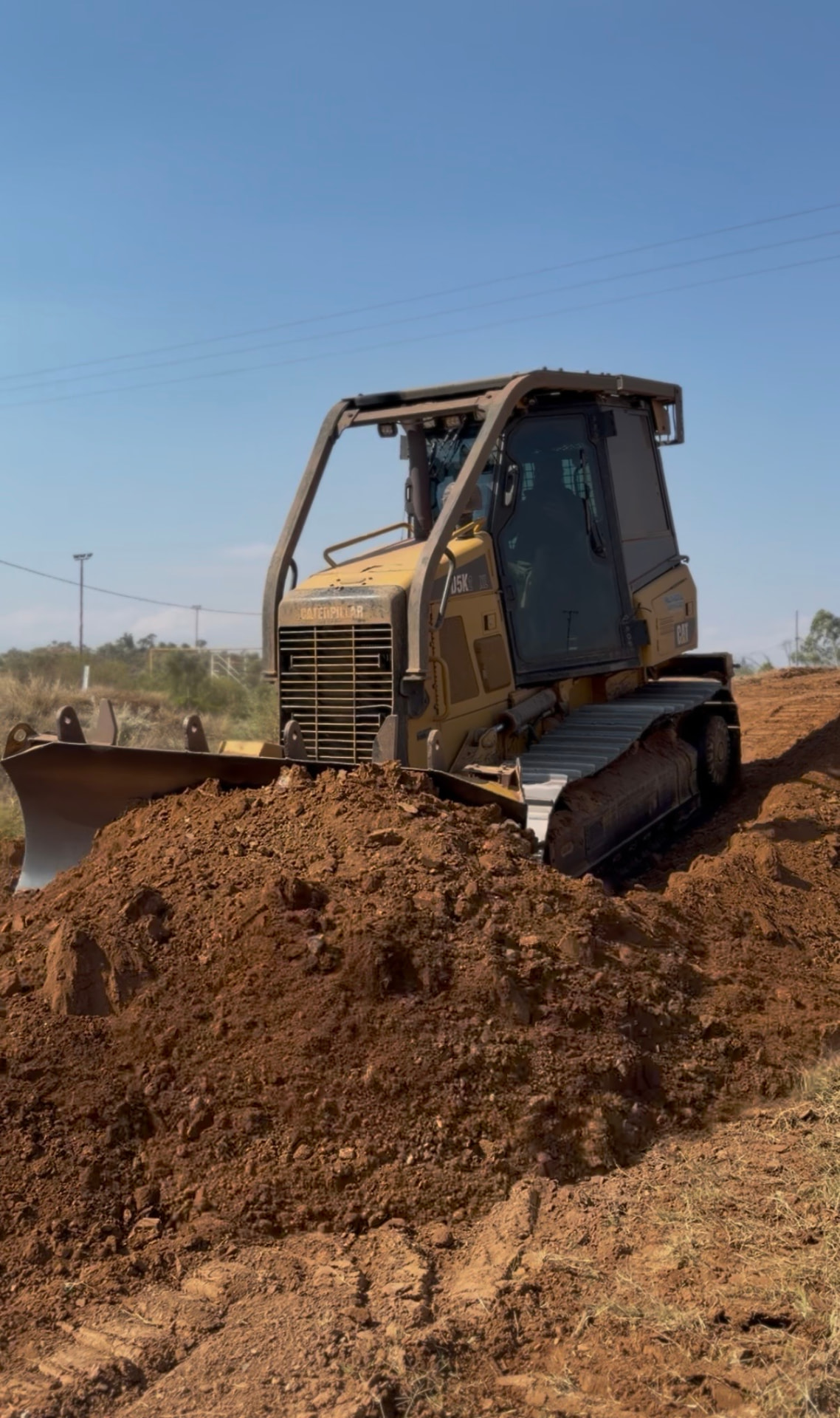 Caterpillar D5K dozer shaping red dirt on the Mount Isa Motocross Club track