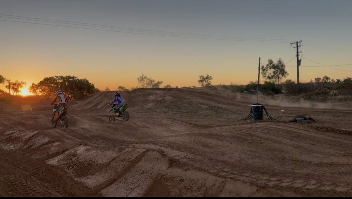 Two young riders taking the first laps on the rebuilt Mount Isa track at sunset