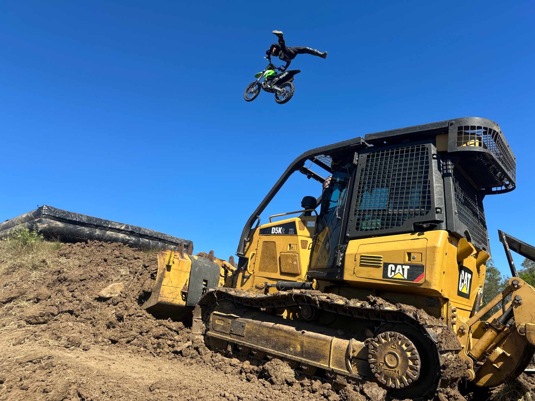 Motocross rider launching a jump in golden hour dust on a Full Throttle built track